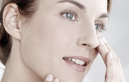 Woman applying cream on her cheekbone