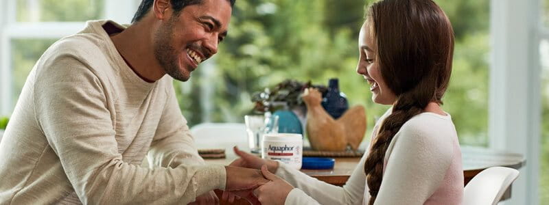 man applying Aquaphor Healing Ointment on daughter's hands