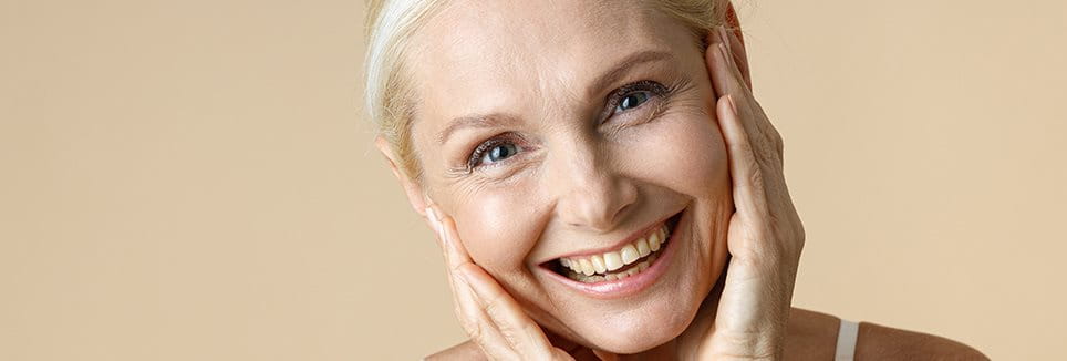 Gesicht einer Frau im mittleren Alter mit deutlich sichtbaren Krähenfüßen und Falten am Auge