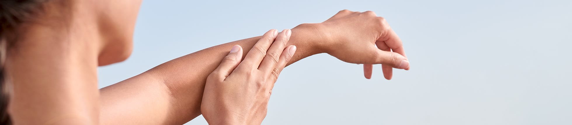 Frau trägt Sonnencreme auf Arm auf
