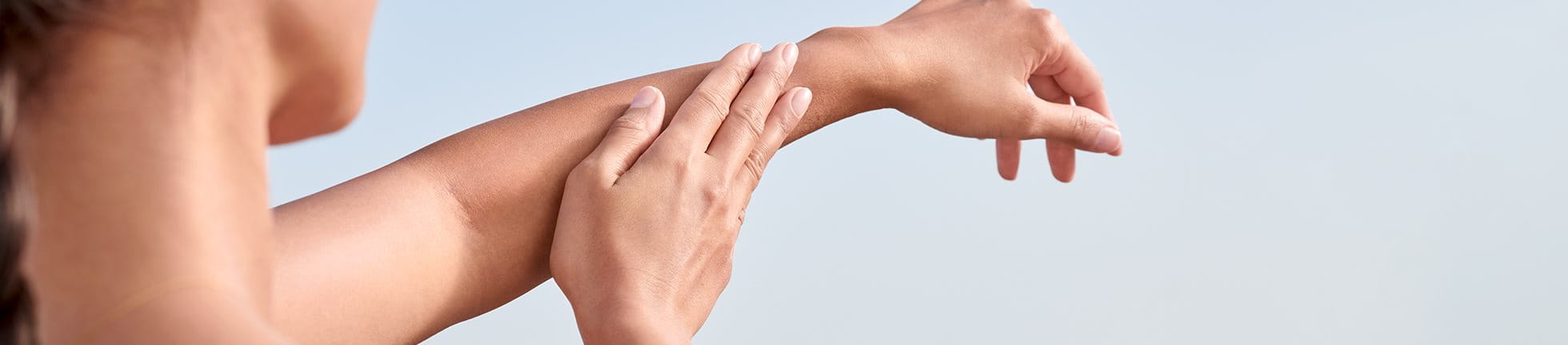 Frau trägt Sonnencreme auf Arm auf