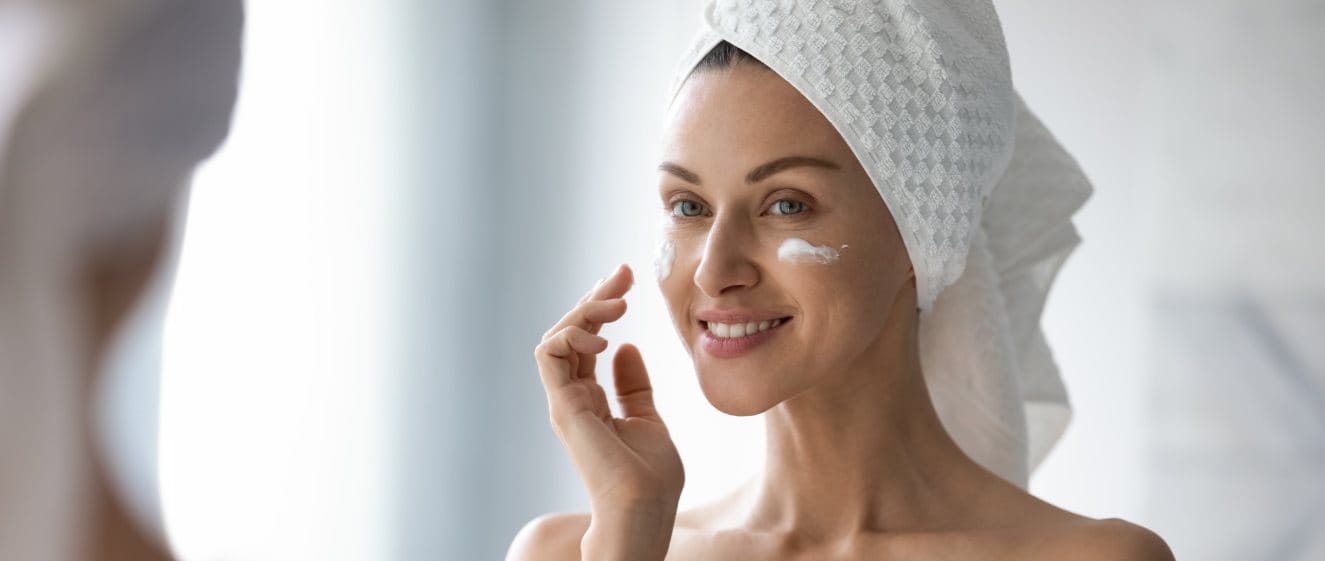 Frau cremt sich mit Biotin Creme ein