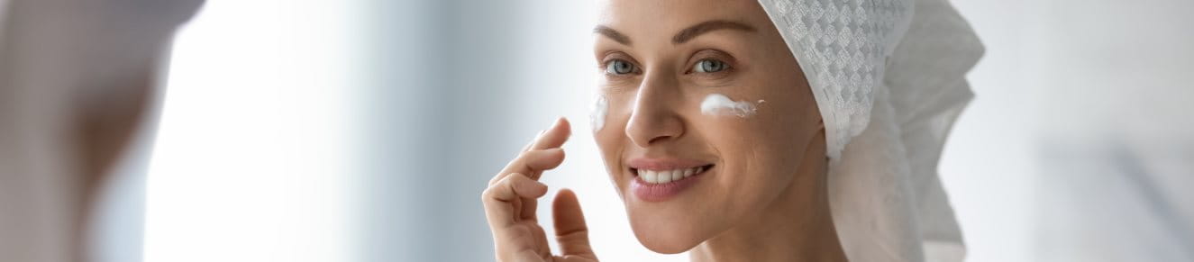 Frau cremt sich mit einer Creme mit Biotin ein