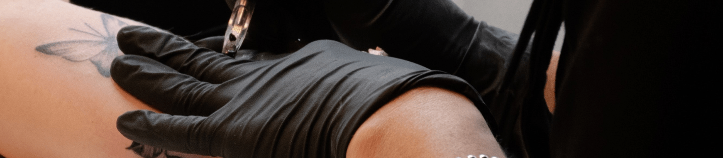 en tatuerare som utför en tatuering