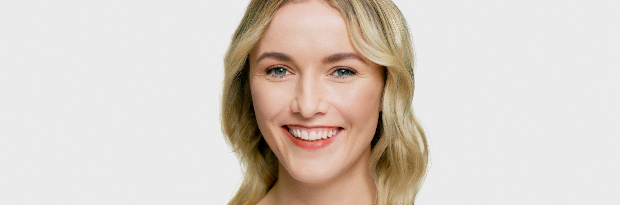 Blonde woman smiling on a grey background