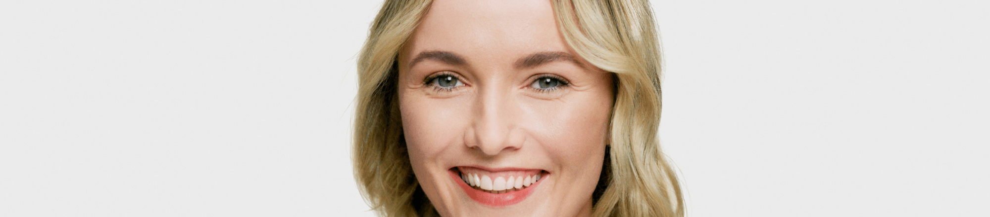 Blonde woman smiling on a grey background