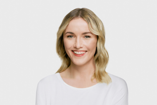 Blonde woman smiling on a grey background