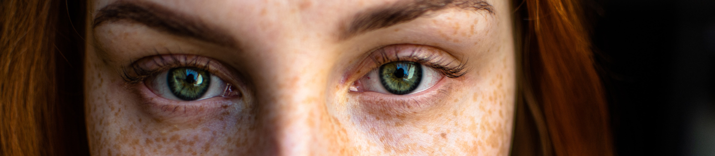 kuva naisesta, jolla on pisamia ja vihreät silmät ja joka katsoo suoraan kameraan