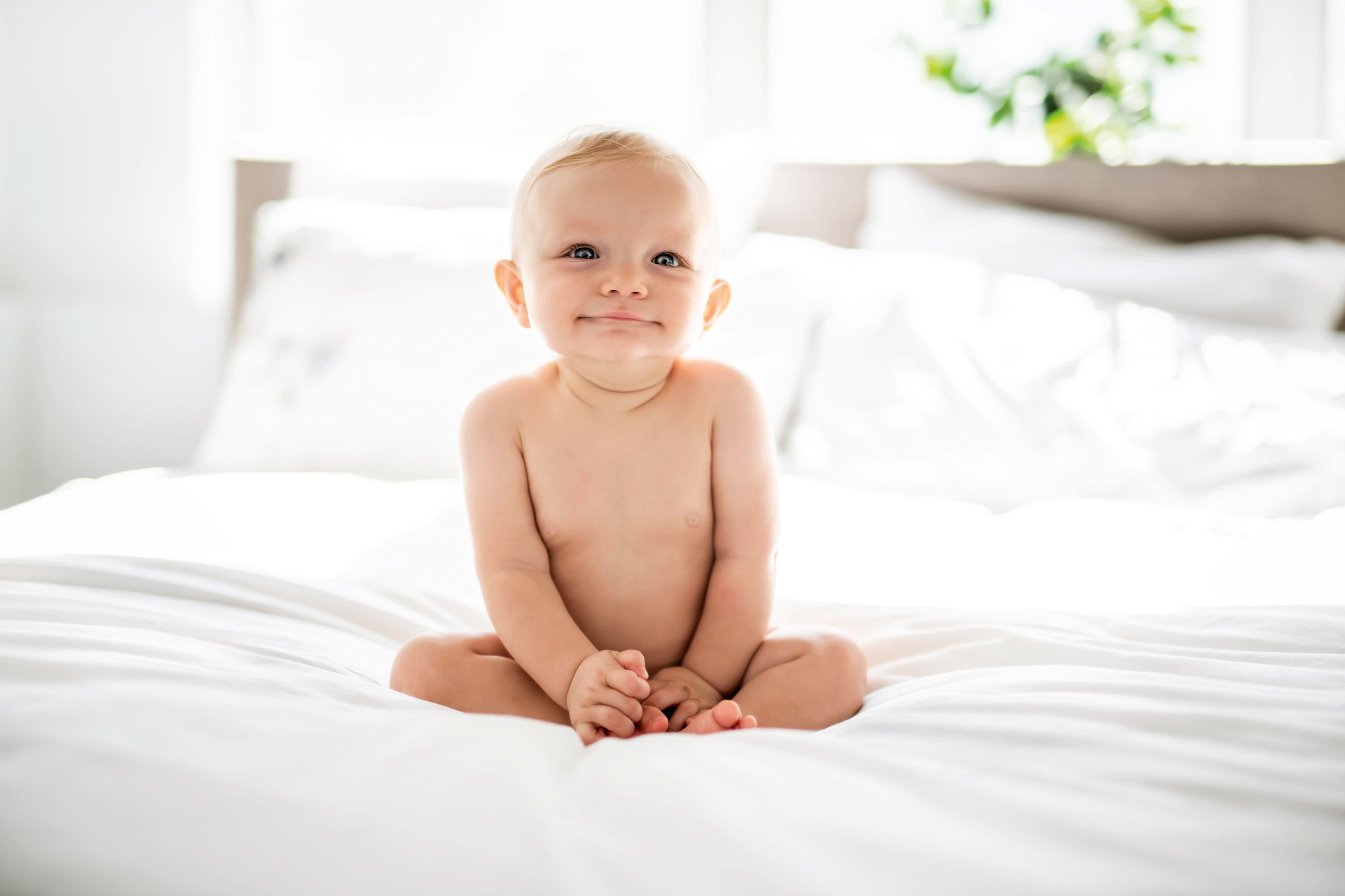 baby smiling on white bed