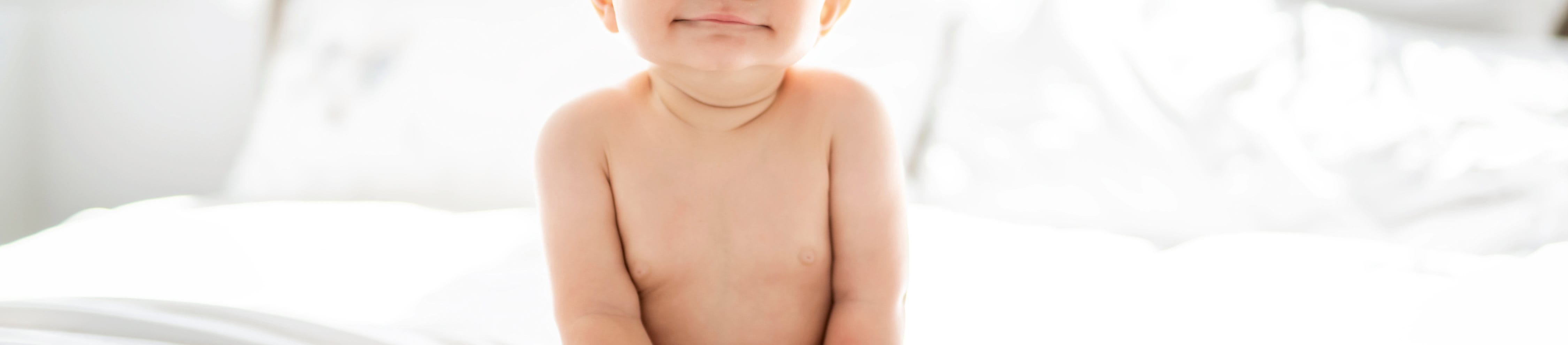 baby smiling on white bed