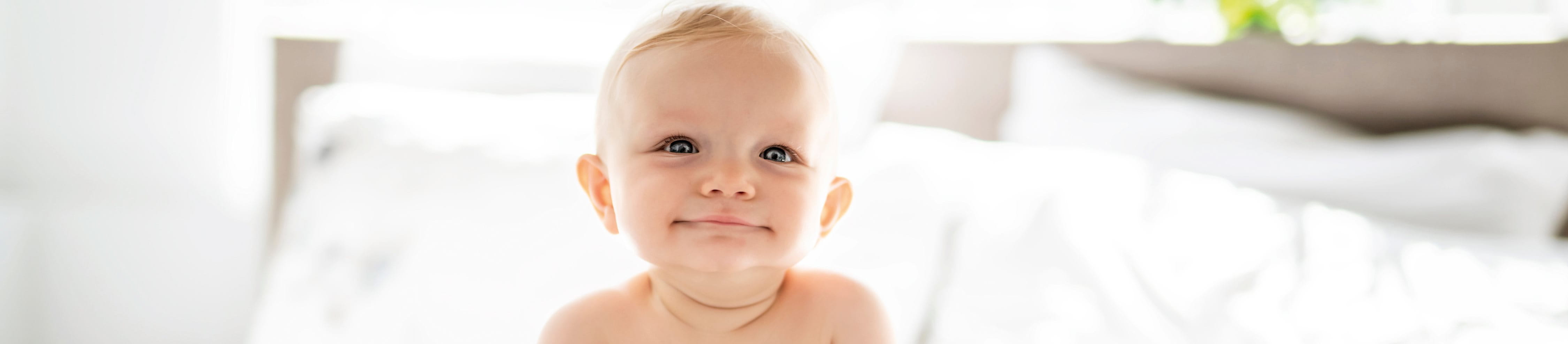 baby smiling on white bed