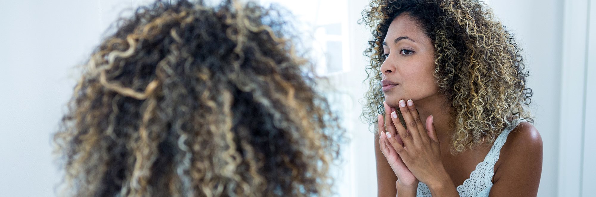 Kvinna undersöker sin känsliga hud i spegeln