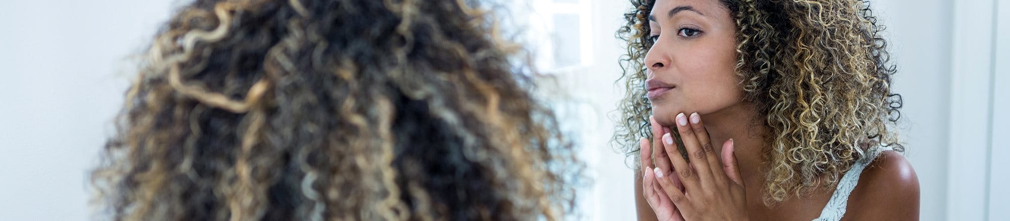 Kvinna undersöker sin känsliga hud i spegeln