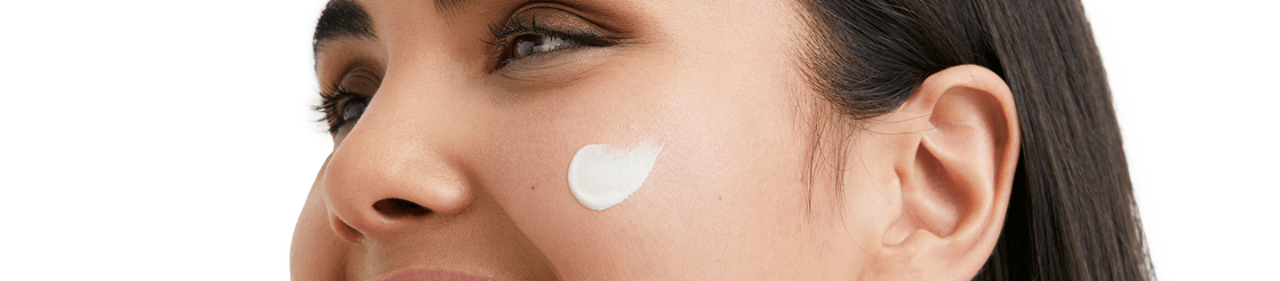 Woman smiling with face cream on her cheek
