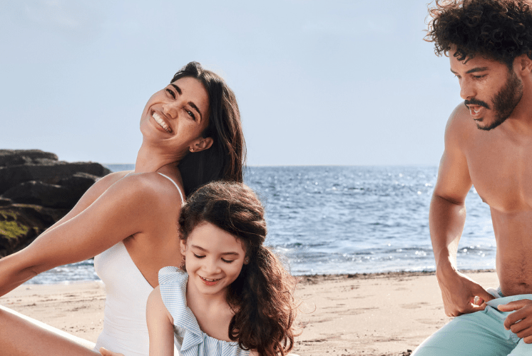 Familj som använder solkräm på stranden