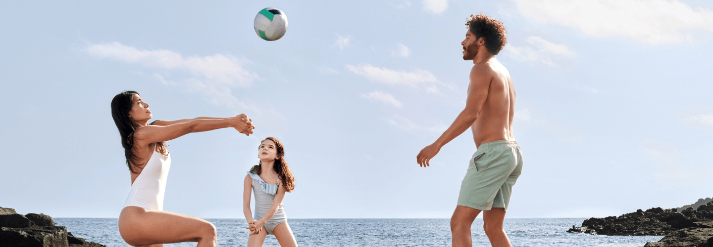 familj som spelar volleyboll på en strand