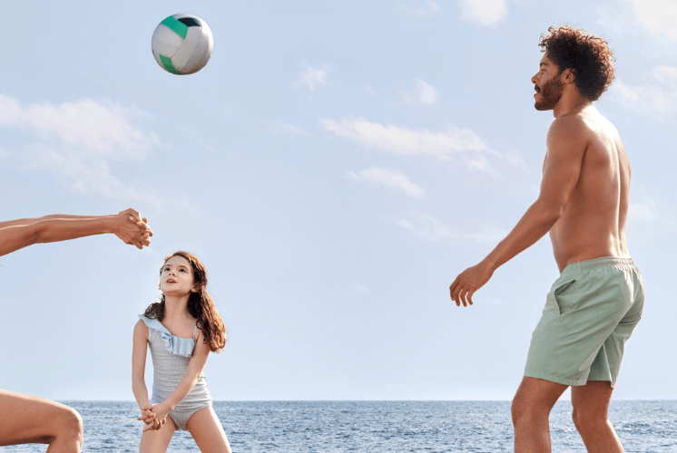 familj som spelar volleyboll på en strand