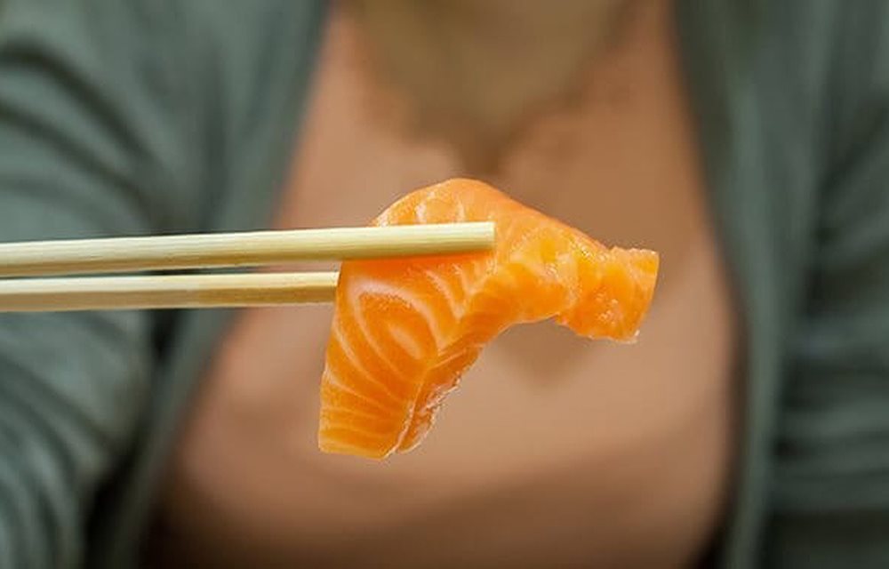 سمك محمول بعيدان الأكل الصيني. زيت السمك يحتوي على أوميغا-3 و هو صحي للبشرة - يوسيرين