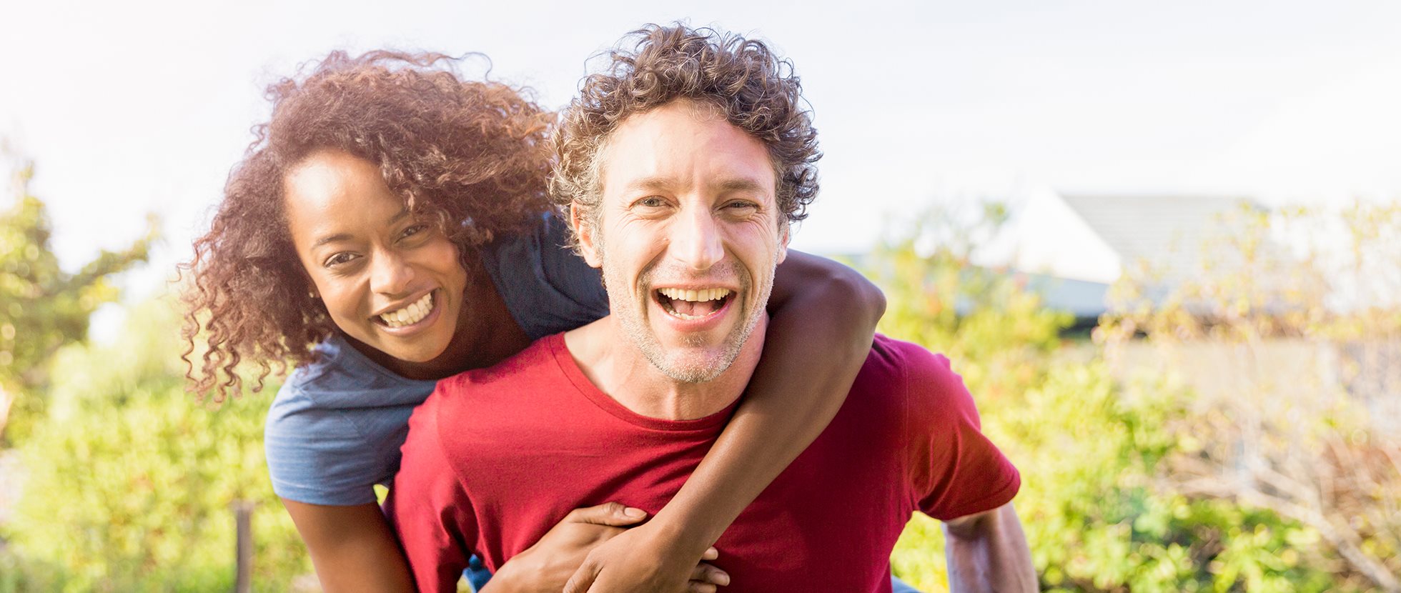 A woman happily piggybacks on a smiling man
