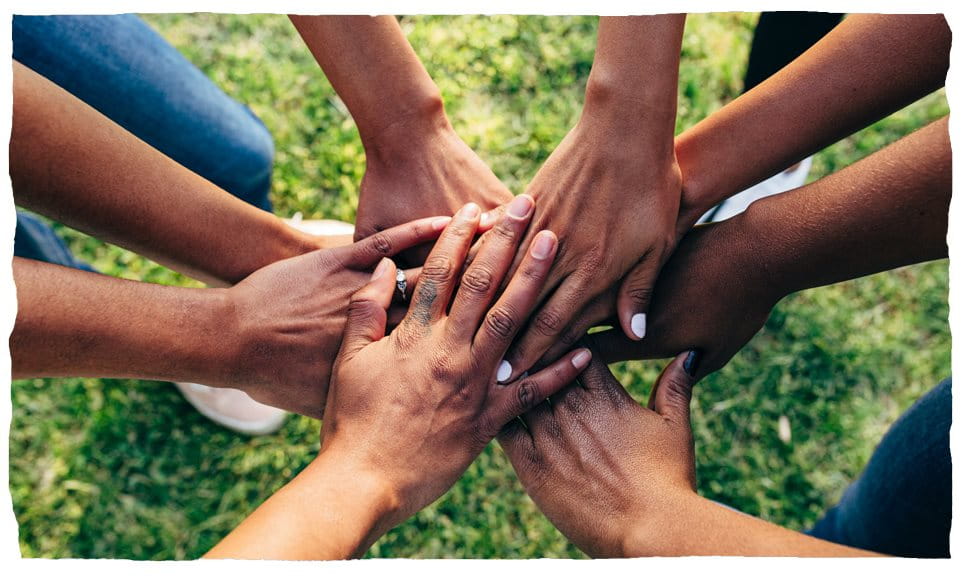People putting their hands together in a circle, symbolizing teamwork.