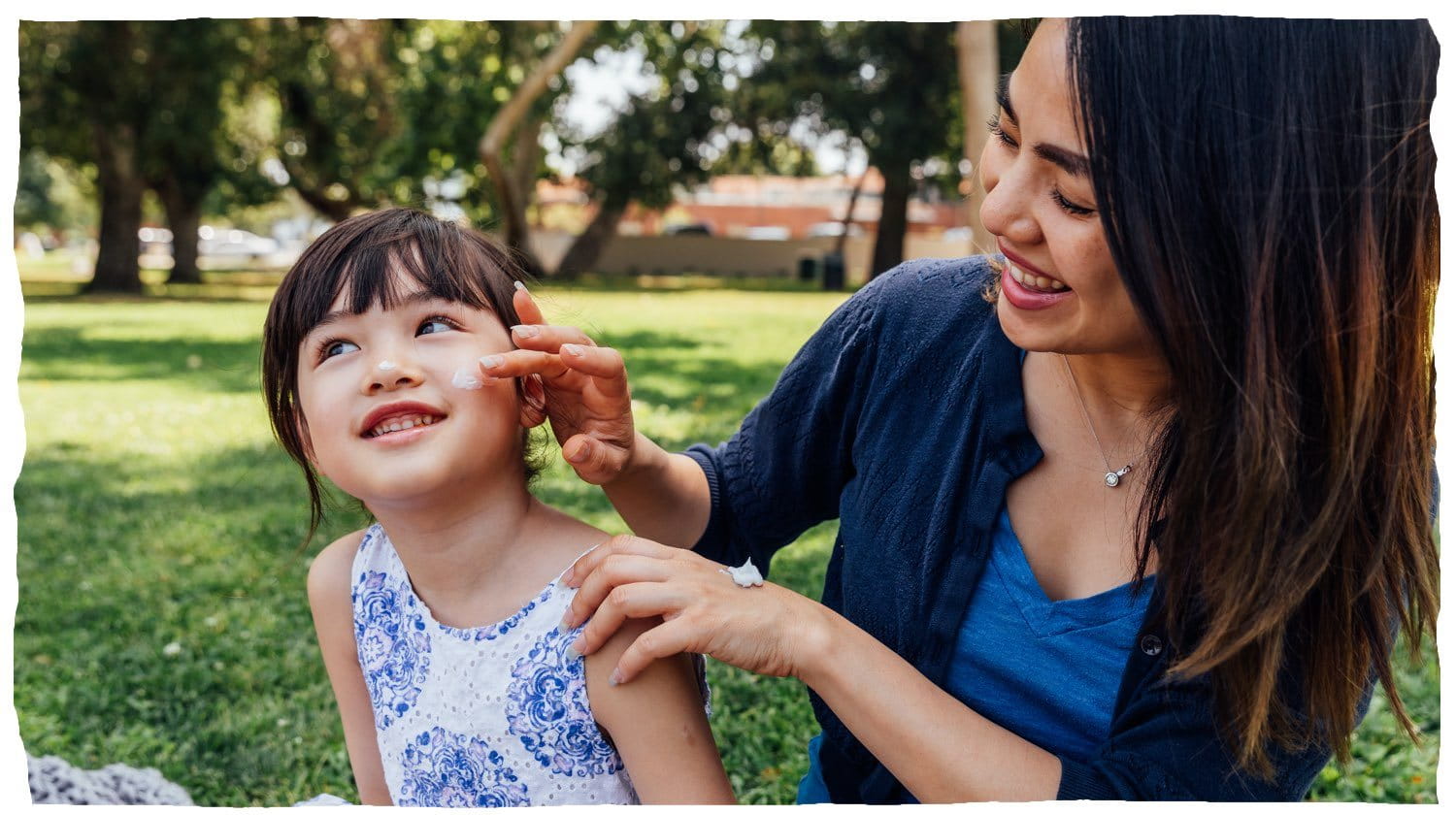 Une femme applique une lotion sur la joue d'un enfant.