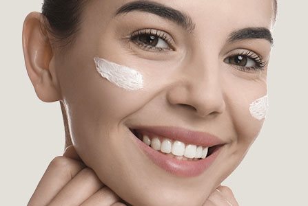 Mujer sonriente con cremas en la cara