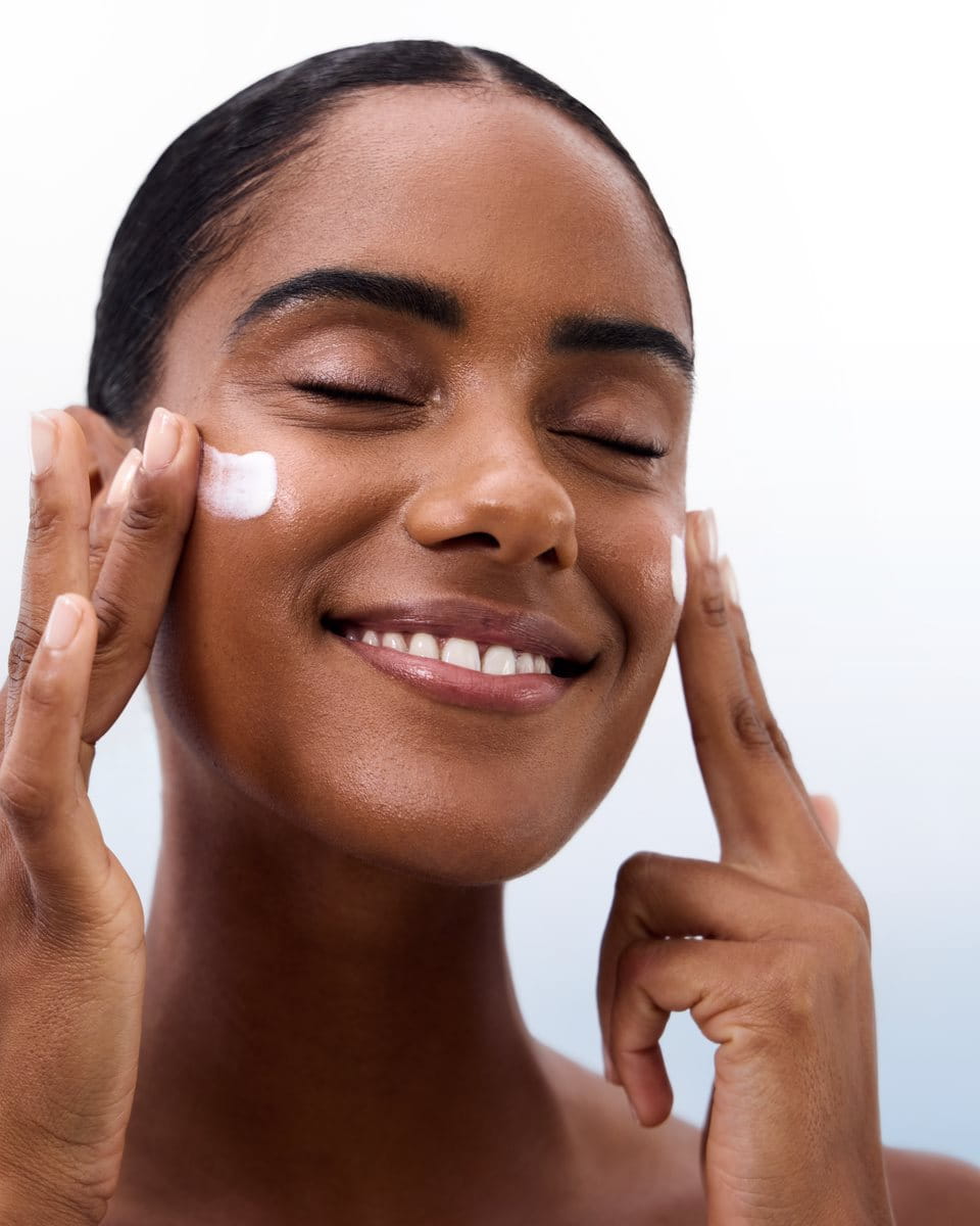 woman applying sunscreen to cheeks