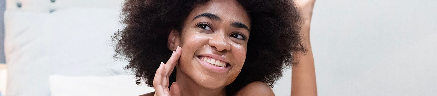 woman rubbing cream on face