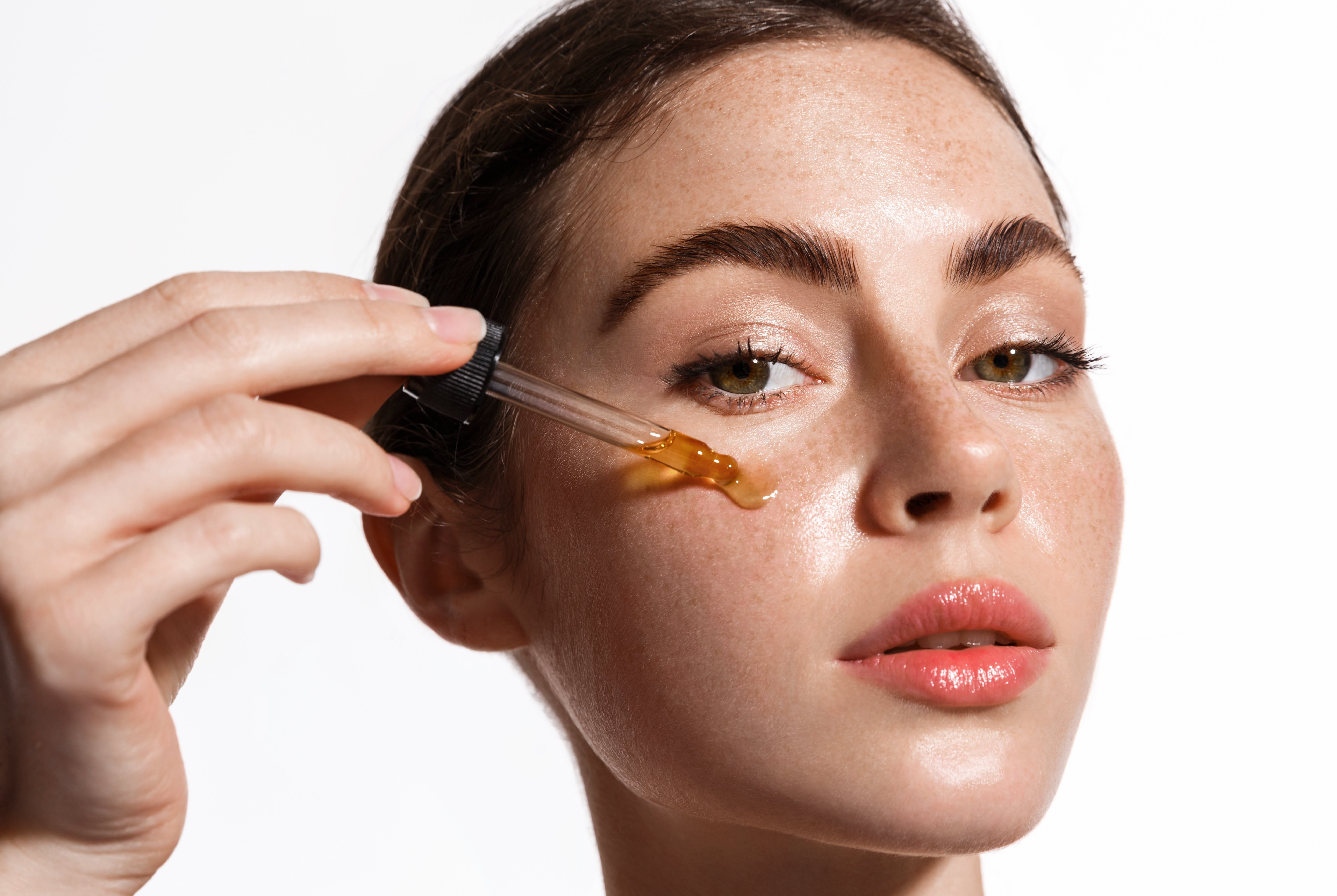 Femme appliquant un sérum visage à l'aide d'une pipette sur sa peau.