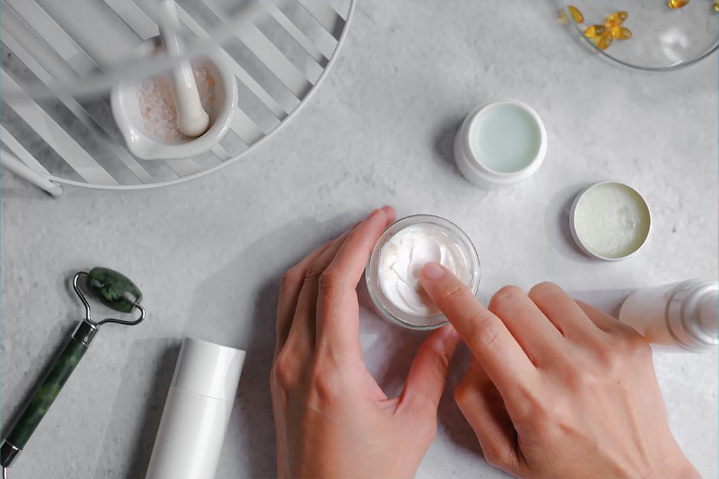 mani femminili che toccano una crema viso o corpo