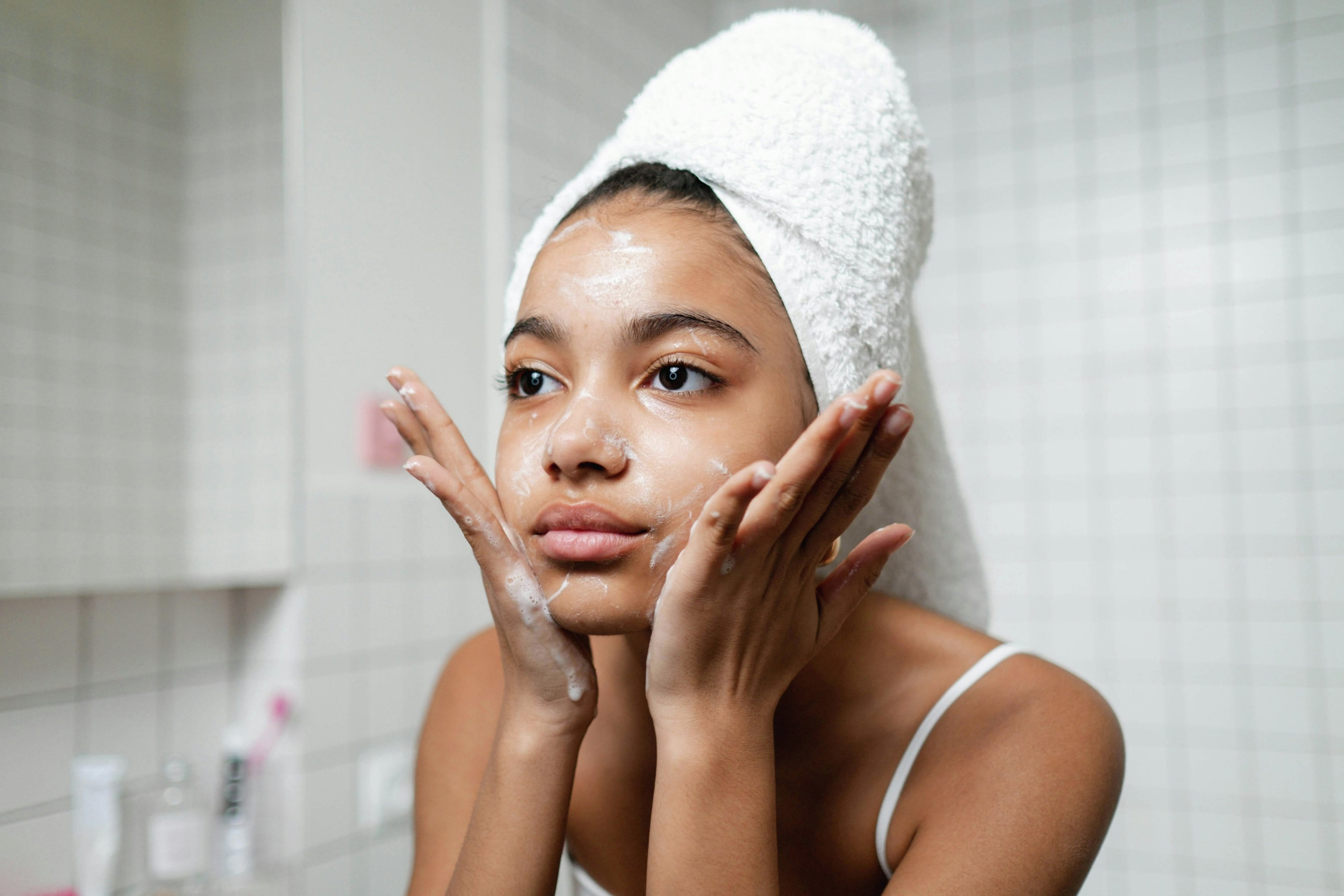 Mädchen reinigt Gesicht mit beiden Händen.