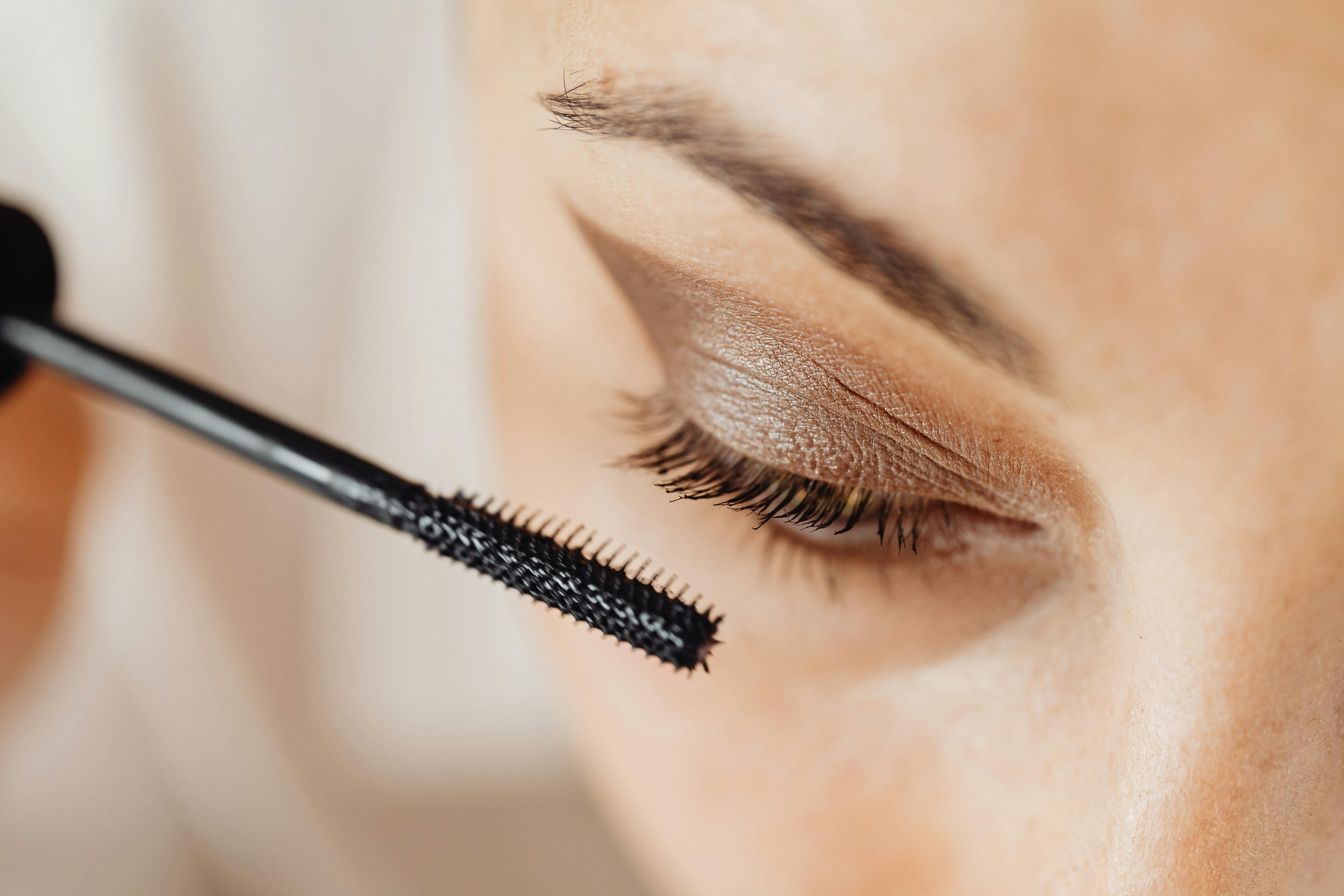 Nahaufnahme des Gesichts einer Frau, die Make-Up auf ihre Augenpartie aufträgt.