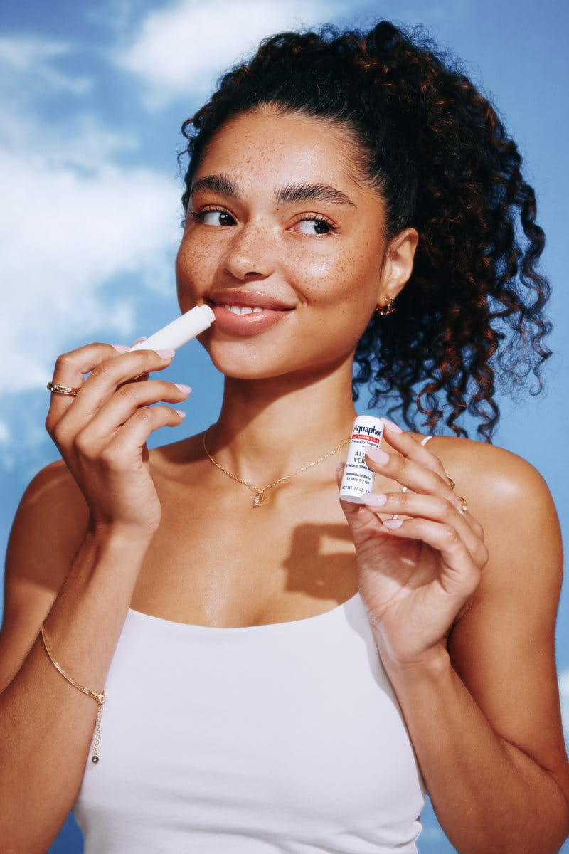 woman applying Aquaphor Lip Naturals