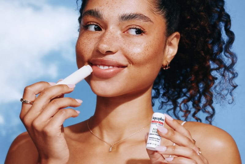 woman applying Aquaphor Lip Naturals
