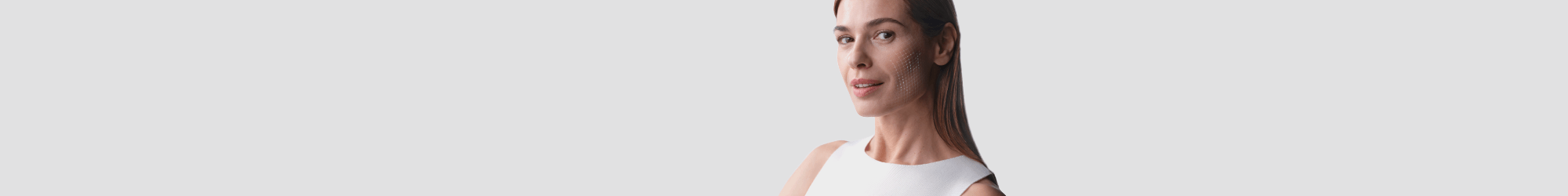 A woman in a white sleeveless shirt on a grey background 