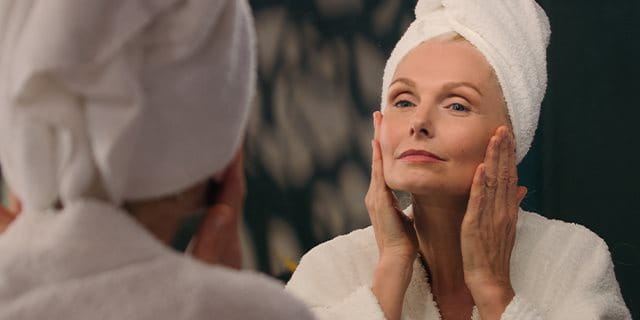 Frau betrachtet Gesicht im Spiegel