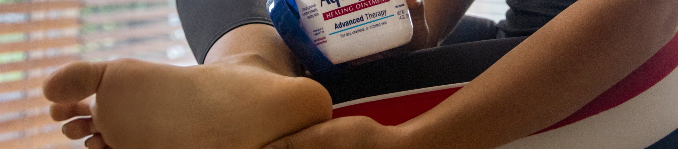 A woman applying Aquaphor to her feet