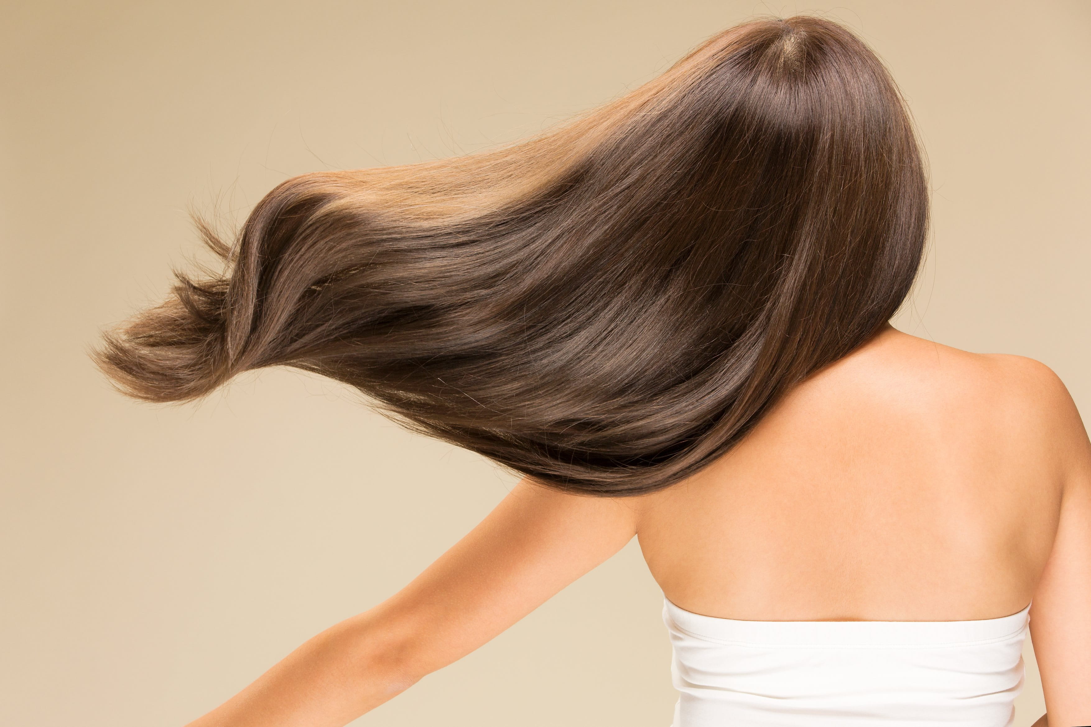 Eine Frau von hinten, dessen lange, braune Haare zur Seite schwingen.