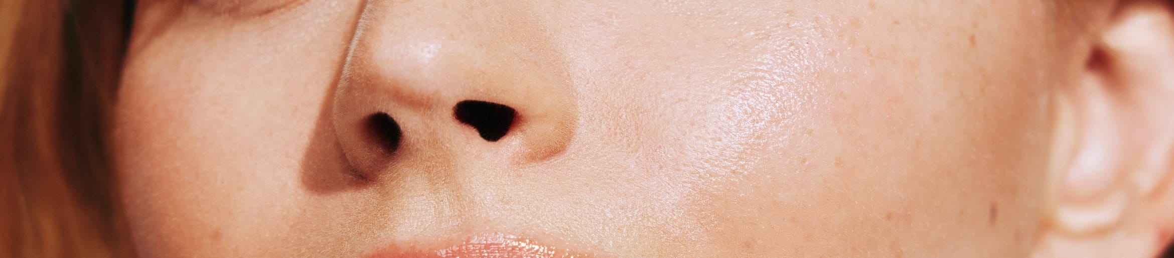 Close-up of a woman’s face showing freckles and smooth, radiant skin.
