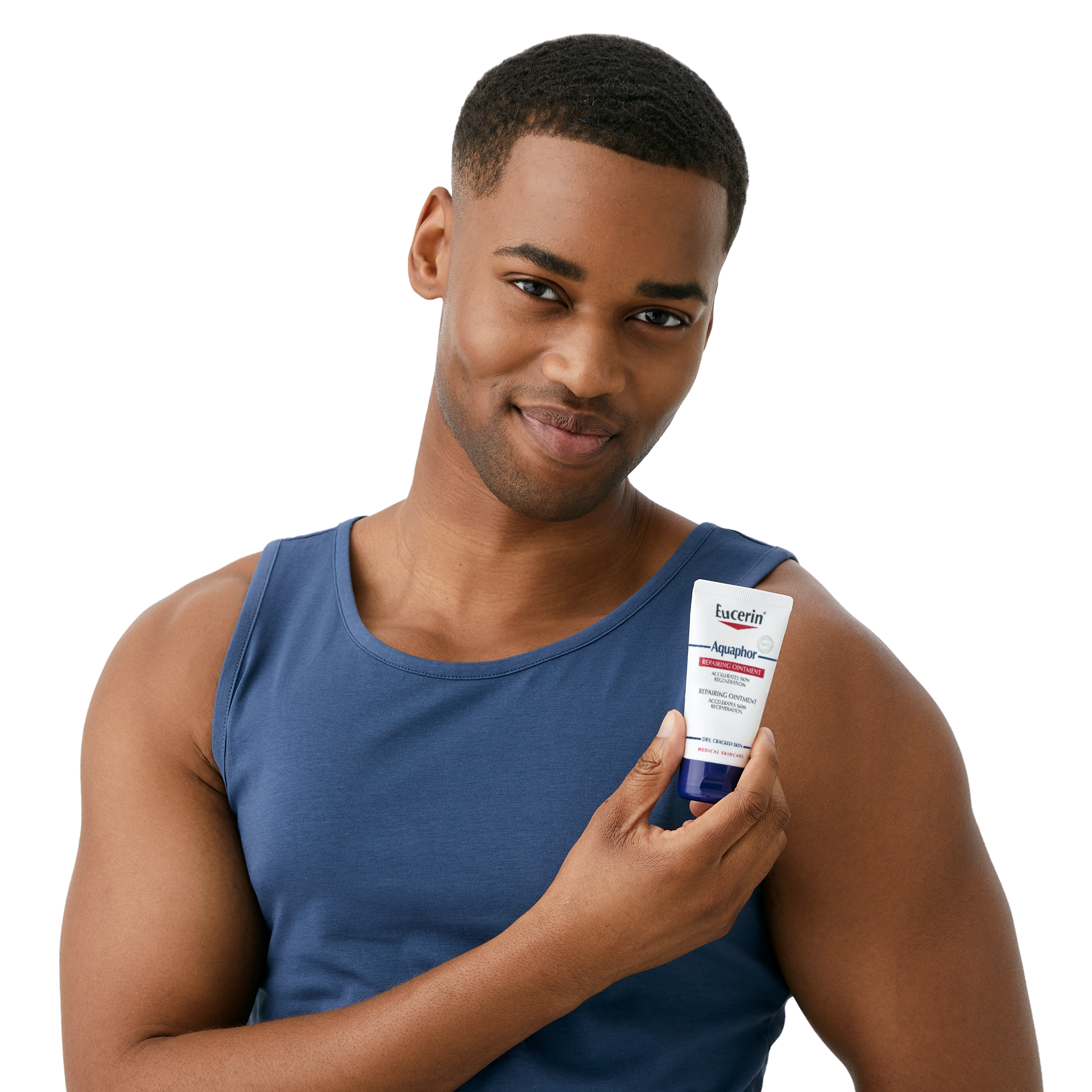 Ein Mann, der eine Tube „Aquaphor Soothing Ointment“ in der Hand hält und lächelnd in die Kamera blickt
