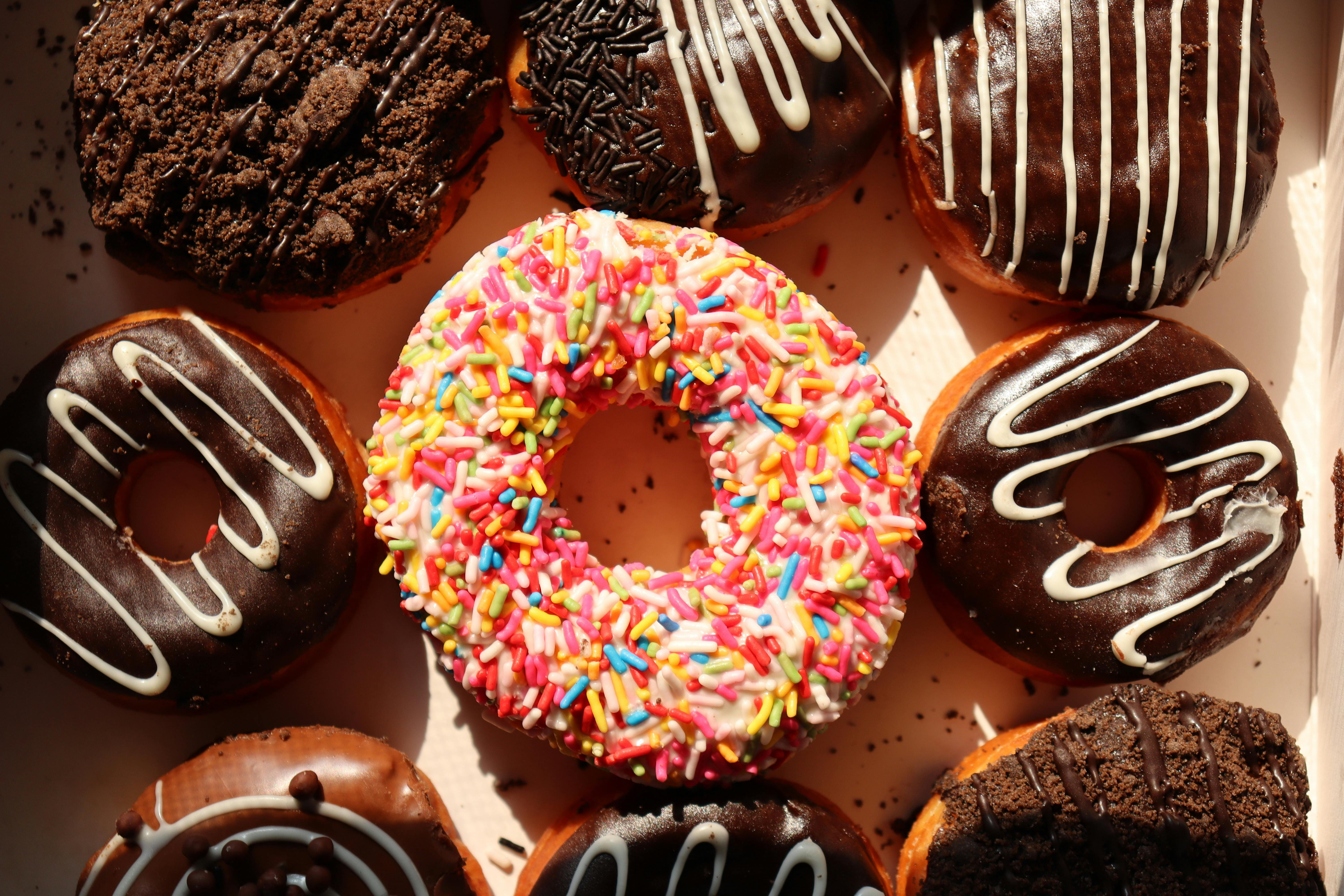 Donuts mit bunten Streuseln und Schokoglasur, die in einer Box liegen