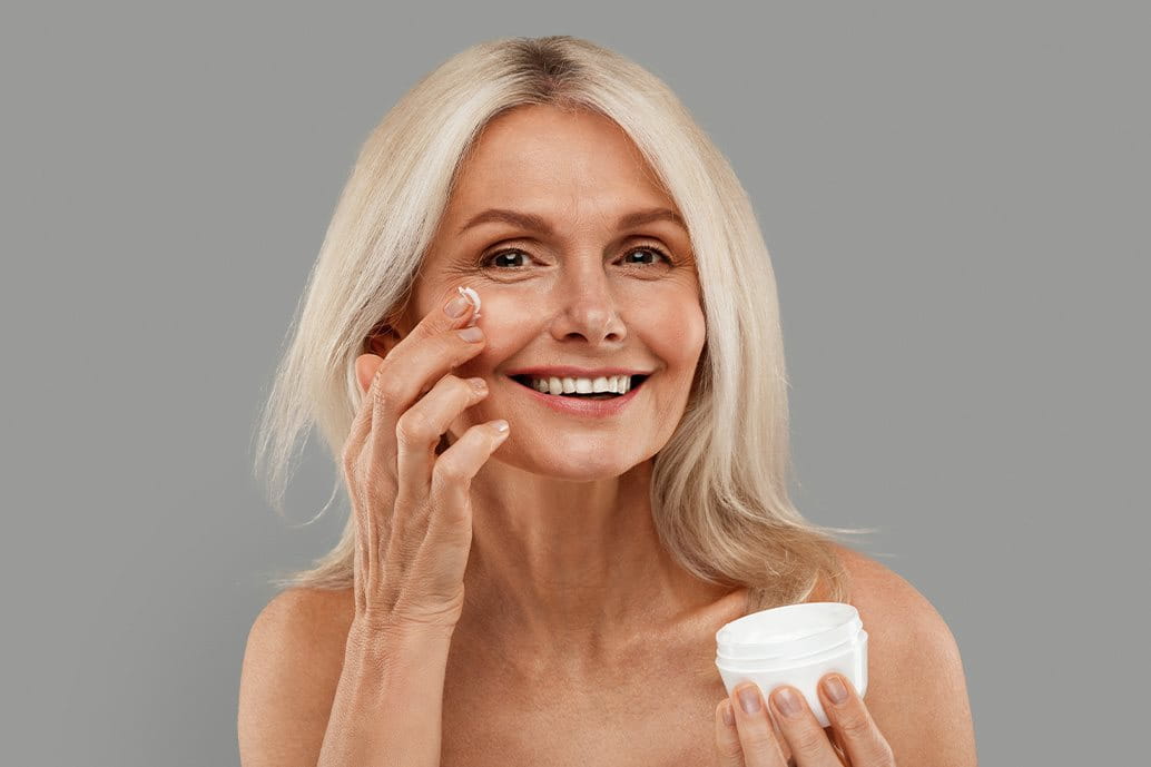donna anziana che applica la crema sul viso