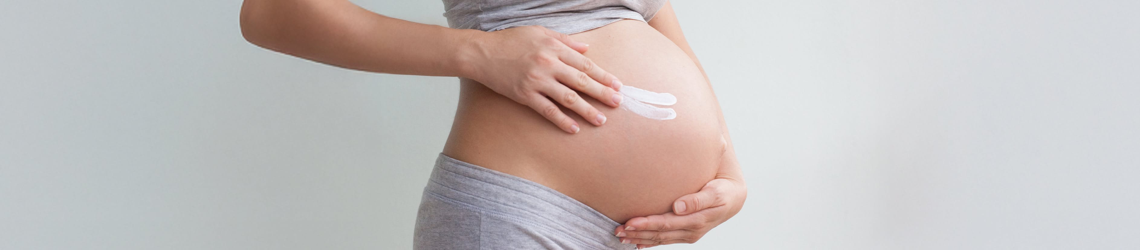 Schwangere Frau mit Creme am Bauch