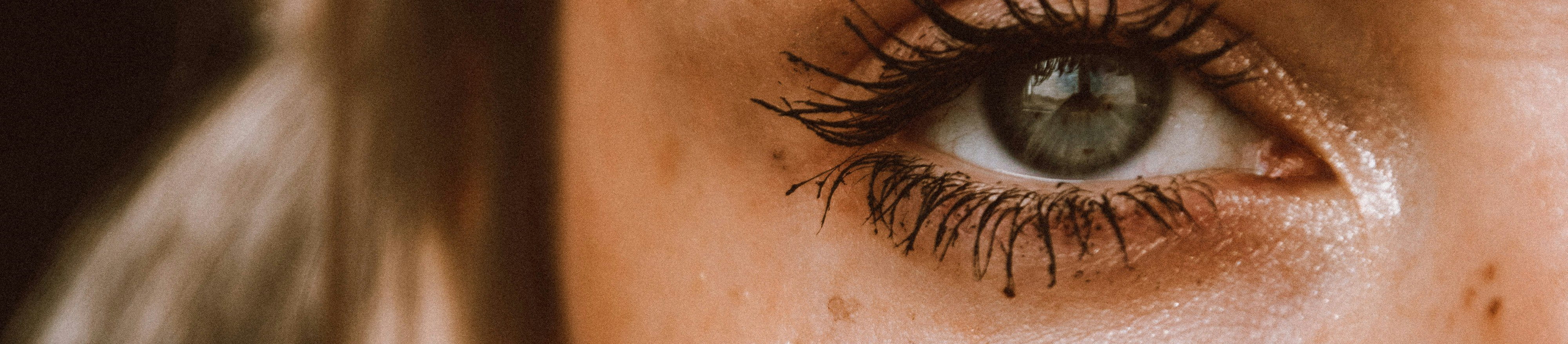 Nahaufnahme der linken Gesichtshälfte einer jungen kaukasischen Frau mit kleinen Pigmentflecken im Bereich der Augenpartie