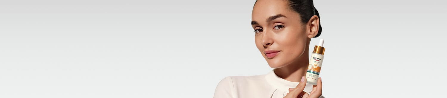 A woman holding Eucerin Sun Face Oil Control Daily UV Serum SPF 50+