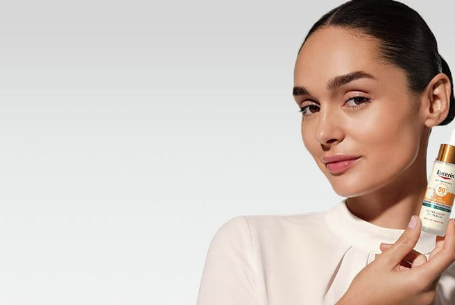 Une femme tenant le Sérum Oil Control Ultra-léger SPF 50+ d’Eucerin