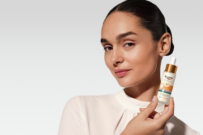 Une femme tenant le Sérum UV Ultra-léger Sun Oil Control SPF 50+ d’Eucerin
