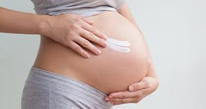 Schwangere Frau mit Creme am Bauch