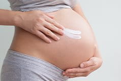 Schwangere Frau mit Creme am Bauch