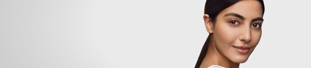 nainen hymyilee katsoessaan peiliin